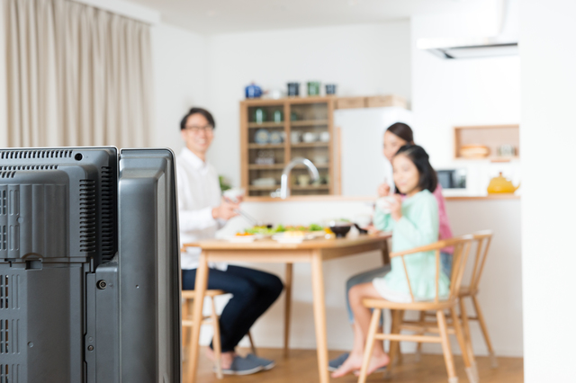 テレビを見ながら食事をする家族