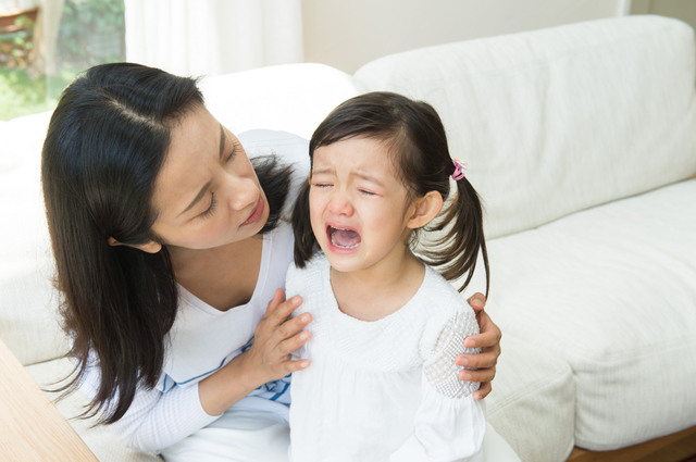 泣く子どもの話を聞くお母さん